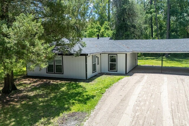 3046 SE 134th St, Starke, FL 32091 - ranch-style house with driveway, an attached carport, a front yard, and roof with shingles