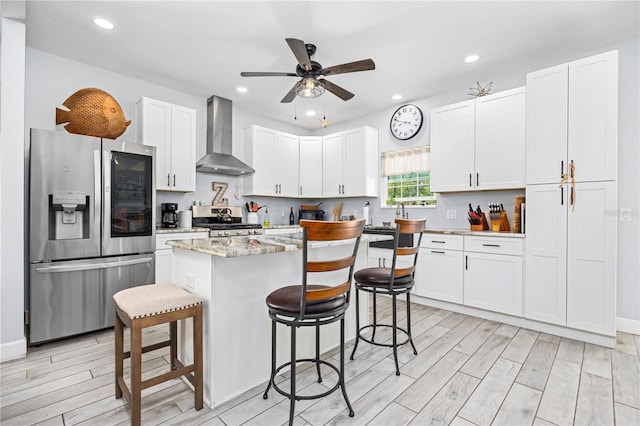 11001 225th Rd, Live Oak, FL 32060 - kitchen with appliances with stainless steel finishes, wall chimney range hood, a breakfast bar, light wood-type flooring, and recessed lighting