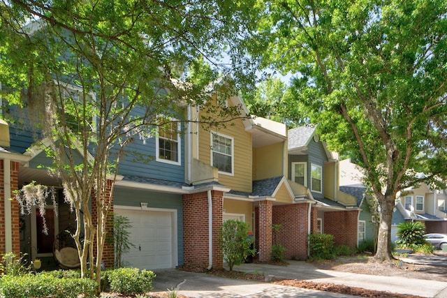multi unit property featuring an attached garage, roof with shingles, brick siding, and driveway