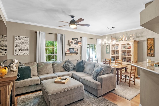 living room with light wood-type flooring, a chandelier, ornamental molding, and a ceiling fan