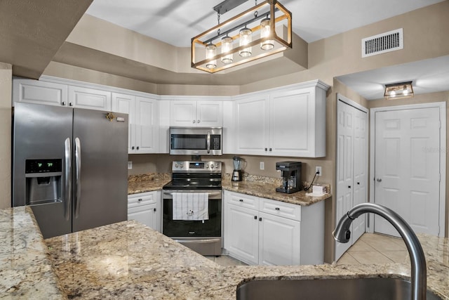 kitchen featuring appliances with stainless steel finishes, a sink, white cabinets, and light stone countertops