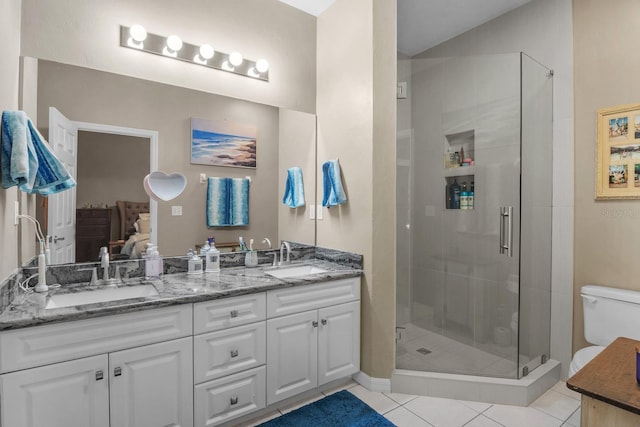ensuite bathroom with a stall shower, double vanity, tile patterned flooring, and toilet