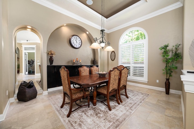 3533 SW 87th Dr, Gainesville, FL 32608 - dining room featuring stone tile floors, baseboards, ornamental molding, arched walkways, and a raised ceiling