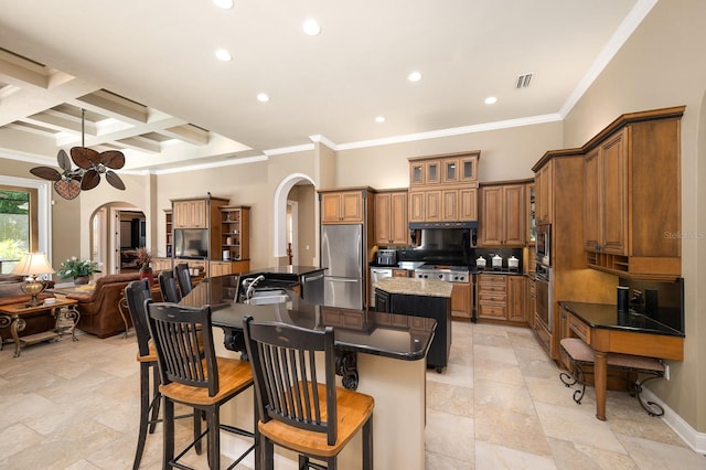 3533 SW 87th Dr, Gainesville, FL 32608 - kitchen with an island with sink, appliances with stainless steel finishes, arched walkways, brown cabinetry, and recessed lighting