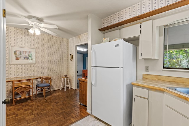 8689 NW 42nd Dr, Gainesville, FL 32653 - kitchen with freestanding refrigerator, wallpapered walls, light countertops, ceiling fan, and white cabinetry