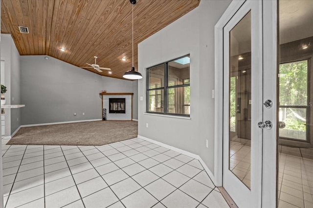 unfurnished living room featuring wooden ceiling, light carpet, a tiled fireplace, vaulted ceiling, and ceiling fan