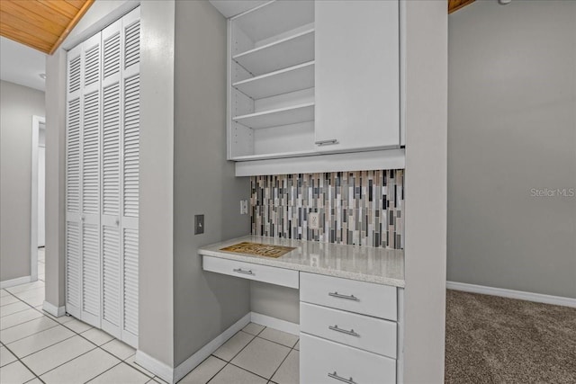 interior space featuring baseboards, light tile patterned floors, and open shelves