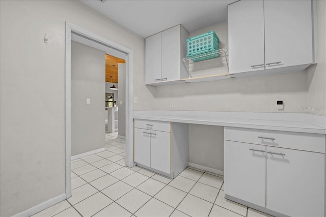 kitchen featuring light countertops, white cabinetry, light tile patterned floors, and baseboards