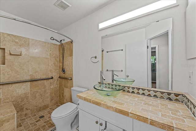 full bathroom with a tile shower, toilet, and vanity