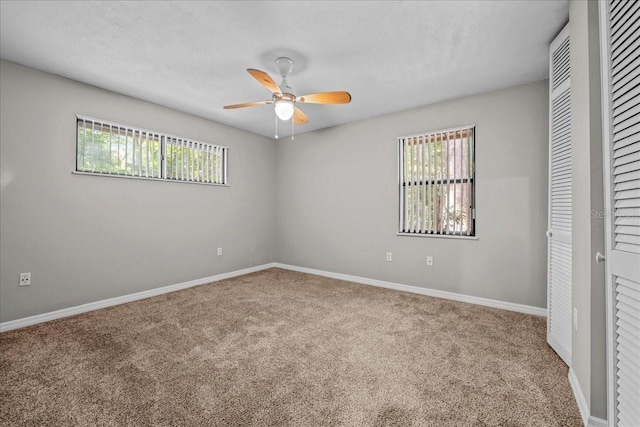 unfurnished bedroom featuring carpet flooring, baseboards, a ceiling fan, and two closets