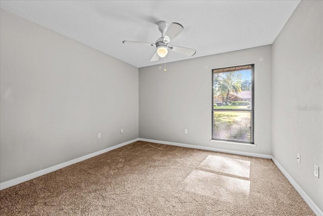 empty room with carpet flooring, a ceiling fan, and baseboards
