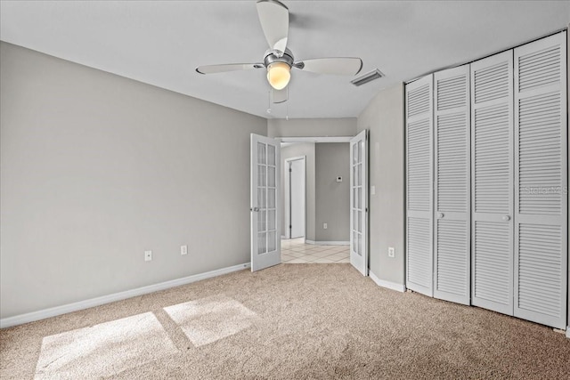 unfurnished bedroom featuring french doors, light carpet, a closet, baseboards, and a ceiling fan