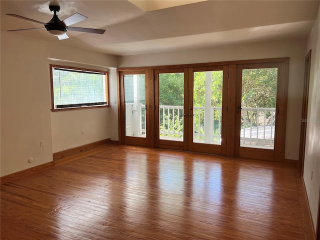 unfurnished room featuring plenty of natural light, baseboards, wood finished floors, and a ceiling fan