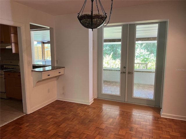 unfurnished dining area featuring baseboards, french doors, and a chandelier