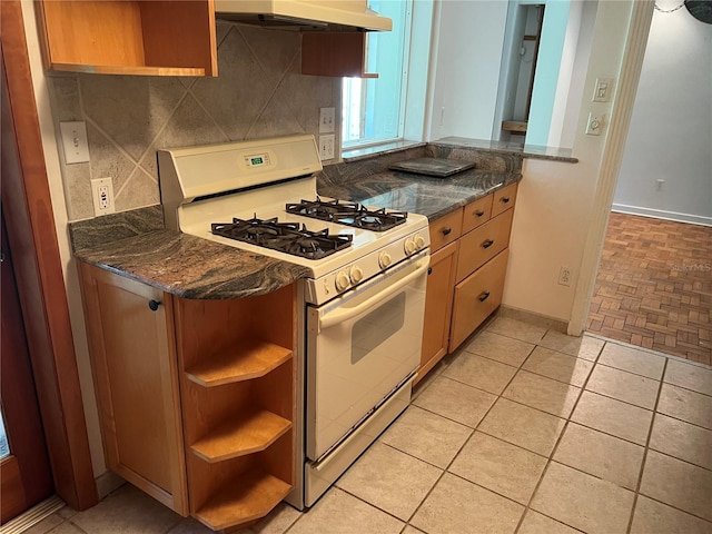 kitchen featuring white range with gas cooktop, open shelves, wall chimney exhaust hood, and baseboards