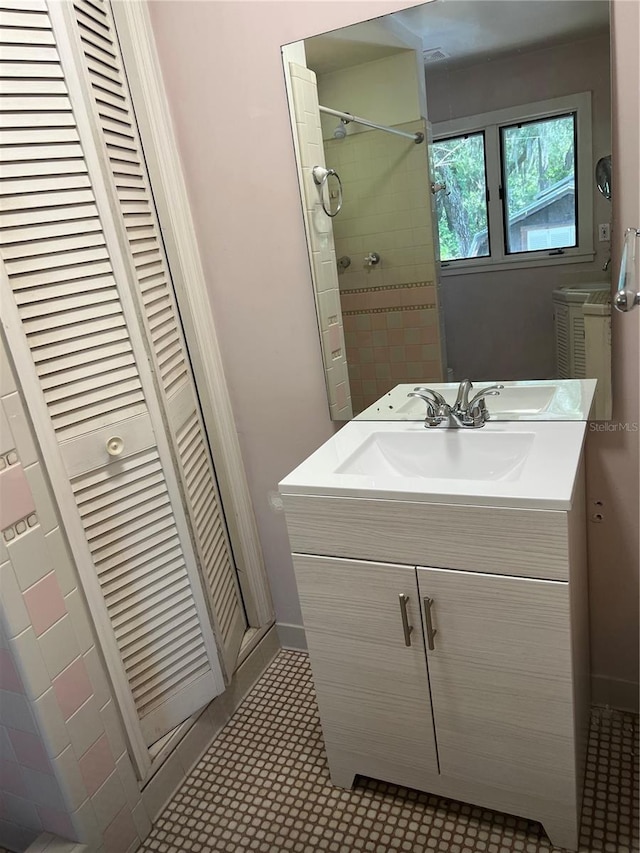 bathroom with vanity, a closet, tiled shower, and baseboards