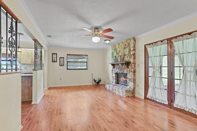 8804 NW 176th Ter, Alachua, FL 32615 - unfurnished living room featuring wood finished floors, a ceiling fan, a stone fireplace, crown molding, and baseboards