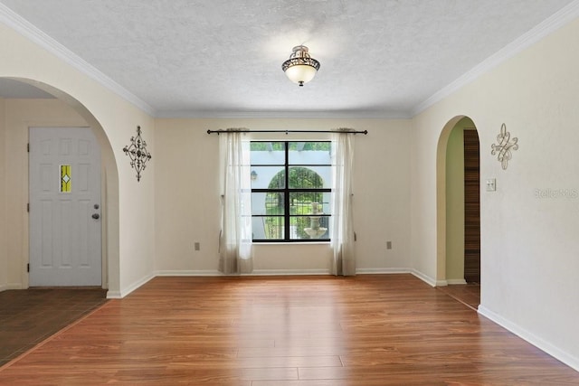 8804 NW 176th Ter, Alachua, FL 32615 - empty room with arched walkways, wood finished floors, ornamental molding, a textured ceiling, and baseboards