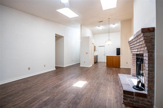231 NW 48th Blvd Unit 0, Gainesville, FL 32607 - unfurnished living room with dark wood-style flooring, a brick fireplace, baseboards, and a skylight