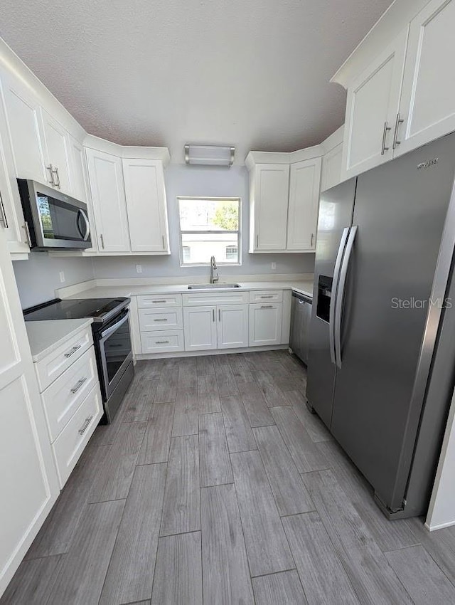 6015 SW 35th Way, Gainesville, FL 32608 - kitchen with stainless steel appliances, a sink, light wood-type flooring, and white cabinets