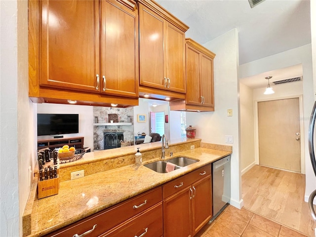 4370 NW 60th Ter, Gainesville, FL 32606 - kitchen with a sink, stainless steel dishwasher, brown cabinetry, light stone countertops, and a stone fireplace