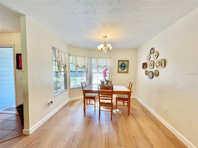4370 NW 60th Ter, Gainesville, FL 32606 - dining space featuring a chandelier, light wood-type flooring, baseboards, and a textured ceiling