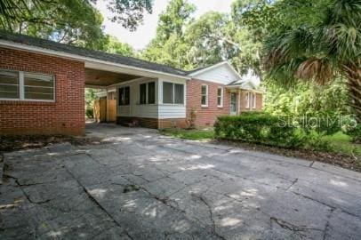 1627 NW 8th Ave, Gainesville, FL 32603 - view of home's exterior featuring brick siding, driveway, and a carport
