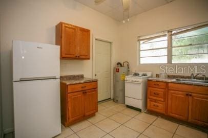 1627 NW 8th Ave, Gainesville, FL 32603 - kitchen featuring white appliances, a sink, brown cabinetry, light tile patterned floors, and electric water heater