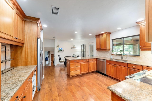 6015 SW 36th Way, Gainesville, FL 32608 - kitchen with stainless steel appliances, a peninsula, light wood finished floors, a sink, and decorative backsplash