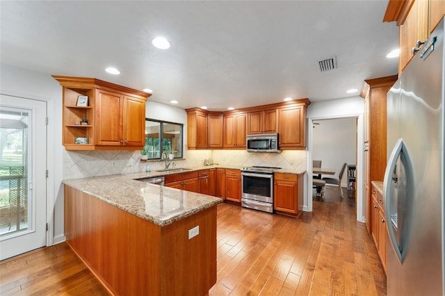 6015 SW 36th Way, Gainesville, FL 32608 - kitchen with stainless steel appliances, a peninsula, a sink, brown cabinets, and recessed lighting