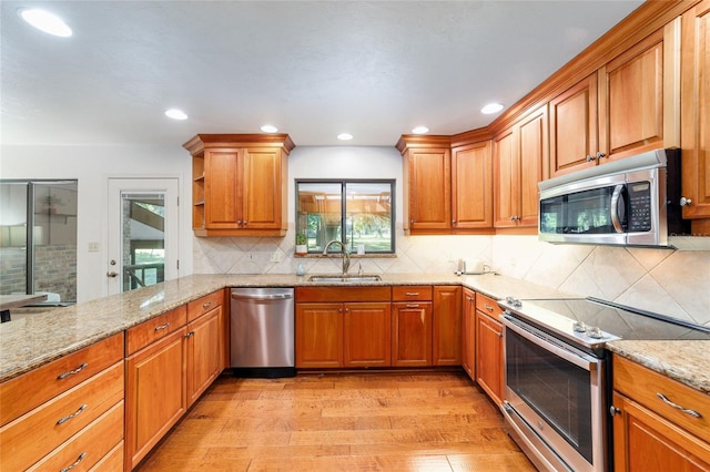 6015 SW 36th Way, Gainesville, FL 32608 - kitchen with appliances with stainless steel finishes, a sink, light stone counters, light wood finished floors, and brown cabinetry