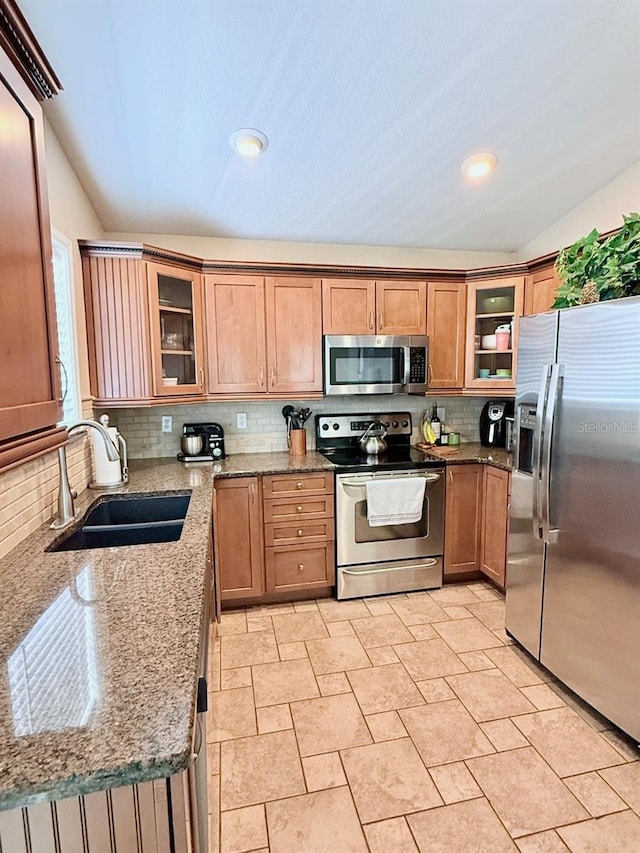 1425 S Central Ave, Flagler Beach, FL 32136 - kitchen featuring appliances with stainless steel finishes, a sink, vaulted ceiling, decorative backsplash, and light stone countertops