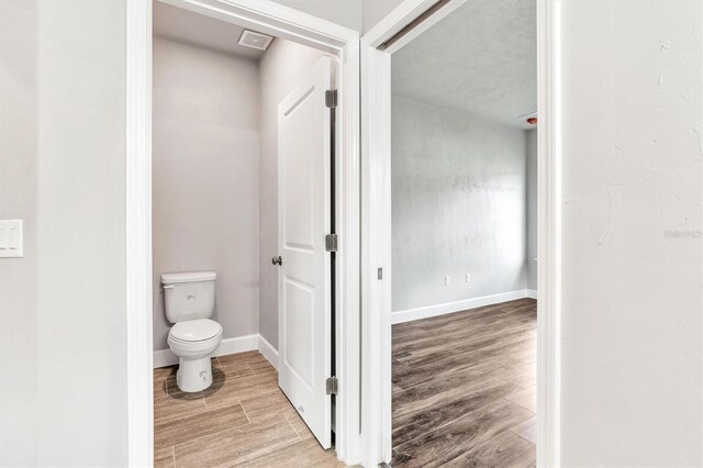 6669 SW 10th Ln, Gainesville, FL 32607 - bathroom featuring wood finished floors, toilet, and baseboards