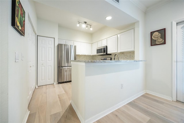 4850 SW 91st Ter Unit P201, Gainesville, FL 32608 - kitchen featuring appliances with stainless steel finishes, light wood-style floors, white cabinets, decorative backsplash, and a peninsula