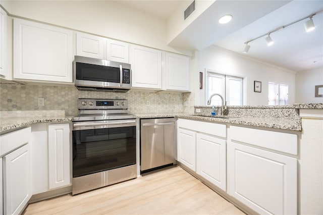 4850 SW 91st Ter Unit P201, Gainesville, FL 32608 - kitchen with stainless steel appliances, a sink, crown molding, light wood-style flooring, and white cabinetry