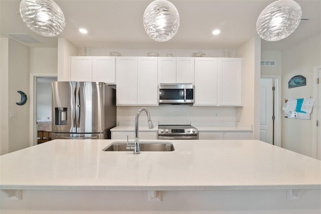 24624 NW 7th Ln, Newberry, FL 32669 - kitchen with stainless steel appliances, a sink, a kitchen island with sink, white cabinetry, and recessed lighting