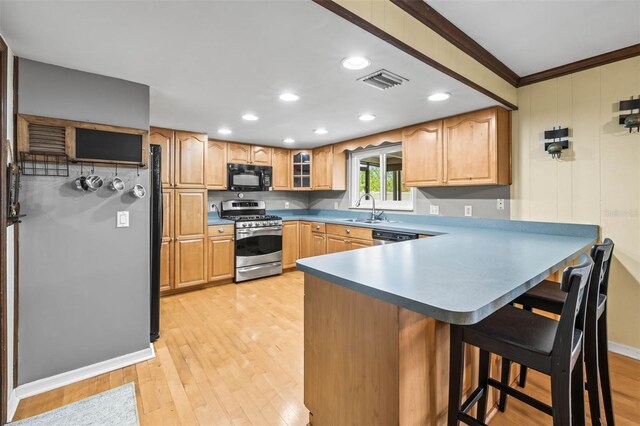 2204 Krista Ln, Brandon, FL 33511 - kitchen with appliances with stainless steel finishes, a sink, a peninsula, a breakfast bar, and light wood-type flooring