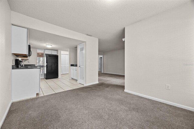 1810 NW 23rd Blvd Unit 203, Gainesville, FL 32605 - unfurnished living room with light colored carpet, a sink, baseboards, light tile patterned floors, and a textured ceiling