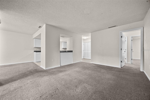 1810 NW 23rd Blvd Unit 203, Gainesville, FL 32605 - unfurnished living room featuring carpet floors, a textured ceiling, and baseboards