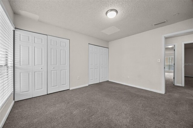 1810 NW 23rd Blvd Unit 203, Gainesville, FL 32605 - unfurnished bedroom with dark colored carpet, multiple closets, a textured ceiling, and baseboards