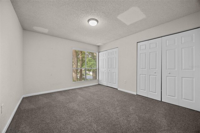 1810 NW 23rd Blvd Unit 203, Gainesville, FL 32605 - unfurnished bedroom with two closets, carpet floors, a textured ceiling, and baseboards