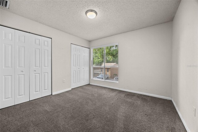 1810 NW 23rd Blvd Unit 203, Gainesville, FL 32605 - unfurnished bedroom featuring multiple closets, carpet floors, a textured ceiling, and baseboards