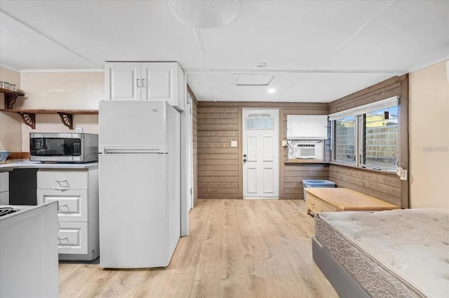 915 S Broadway Unit Ab, Englewood, FL 34223 - kitchen with freestanding refrigerator, stainless steel microwave, white cabinetry, light wood finished floors, and crown molding