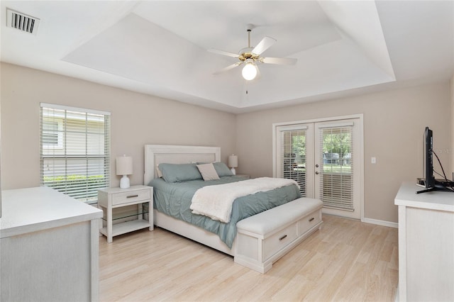 6806 NW 105th Ave, Alachua, FL 32615 - bedroom featuring a tray ceiling, access to outside, french doors, light wood-style floors, and multiple windows