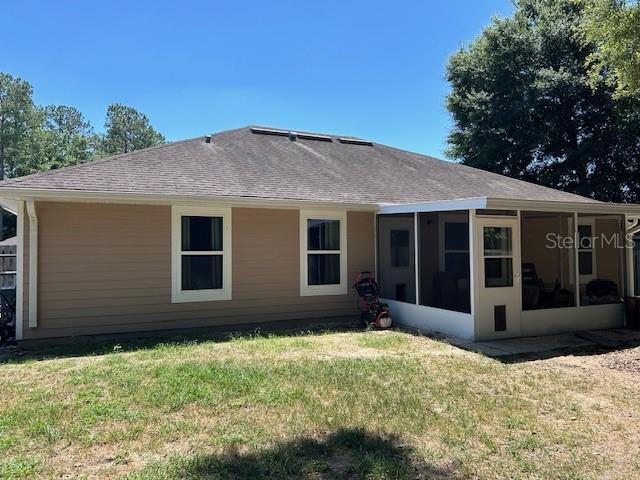 15628 NW 137th Way, Alachua, FL 32615 - rear view of house featuring a sunroom, a yard, and roof with shingles