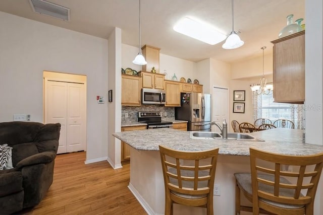 15628 NW 137th Way, Alachua, FL 32615 - kitchen with stainless steel appliances, a sink, a peninsula, a kitchen breakfast bar, and backsplash