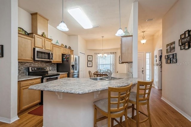 15628 NW 137th Way, Alachua, FL 32615 - kitchen featuring stainless steel appliances, a sink, a peninsula, wood finished floors, and a breakfast bar