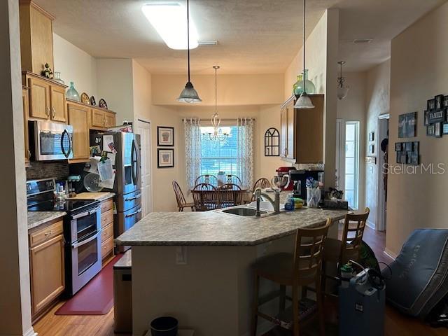 15628 NW 137th Way, Alachua, FL 32615 - kitchen with appliances with stainless steel finishes, a sink, a kitchen bar, a peninsula, and wood finished floors