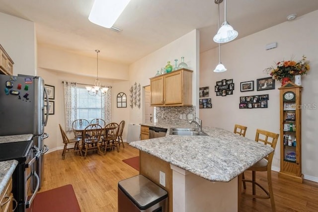 15628 NW 137th Way, Alachua, FL 32615 - kitchen featuring a sink, a breakfast bar, light wood finished floors, appliances with stainless steel finishes, and a peninsula