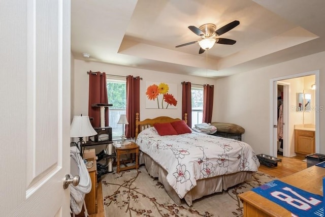 15628 NW 137th Way, Alachua, FL 32615 - bedroom with a raised ceiling, light wood-style flooring, ceiling fan, and connected bathroom